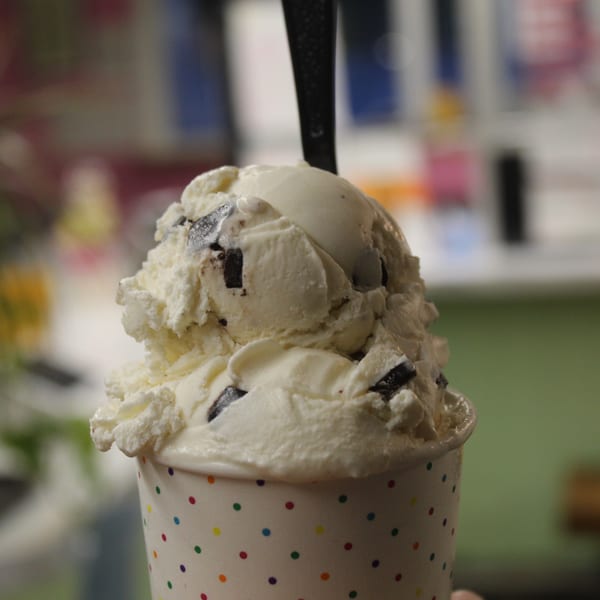 Close-up of chocolate chip ice cream in a white polka dot cup with a spoon.
